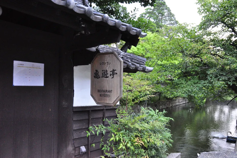木製看板と植栽があるレストラン 亀遊亭の入口