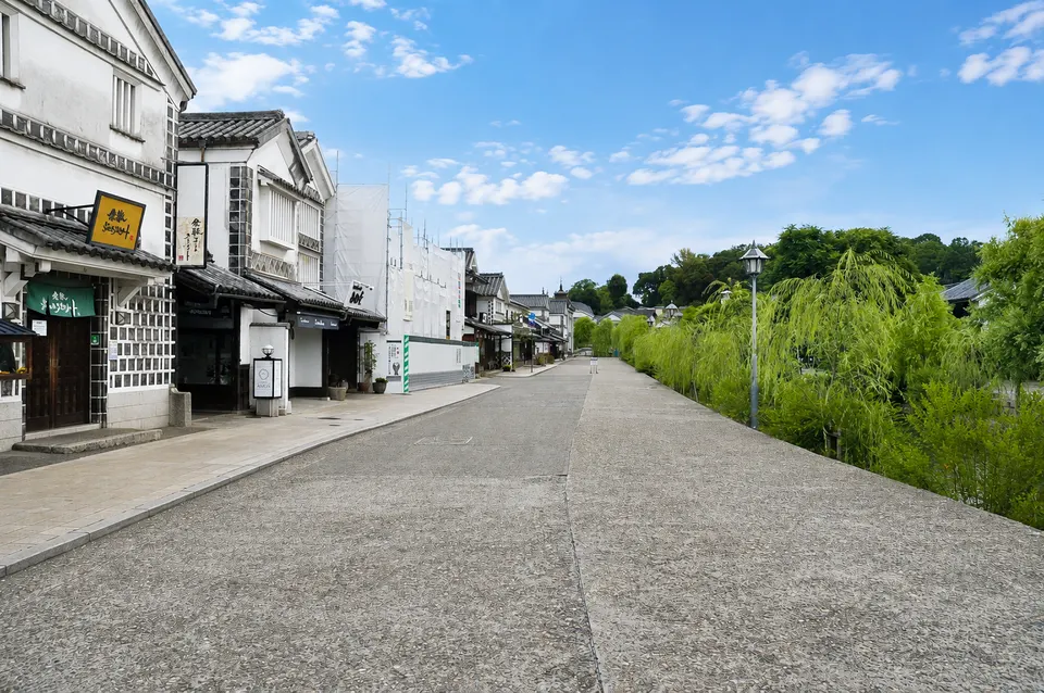 白壁の建物と柳が続く倉敷川沿いの通り
