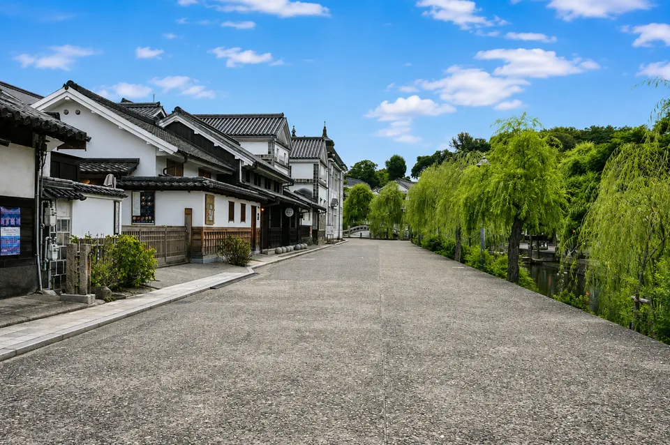 白壁の町家と柳が並ぶ倉敷川沿いの道